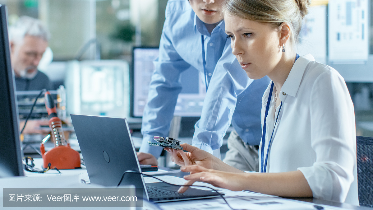 女計算機科學家將電路板連接到她的筆記本電腦并開始編程。她在先進技術實驗室工作。